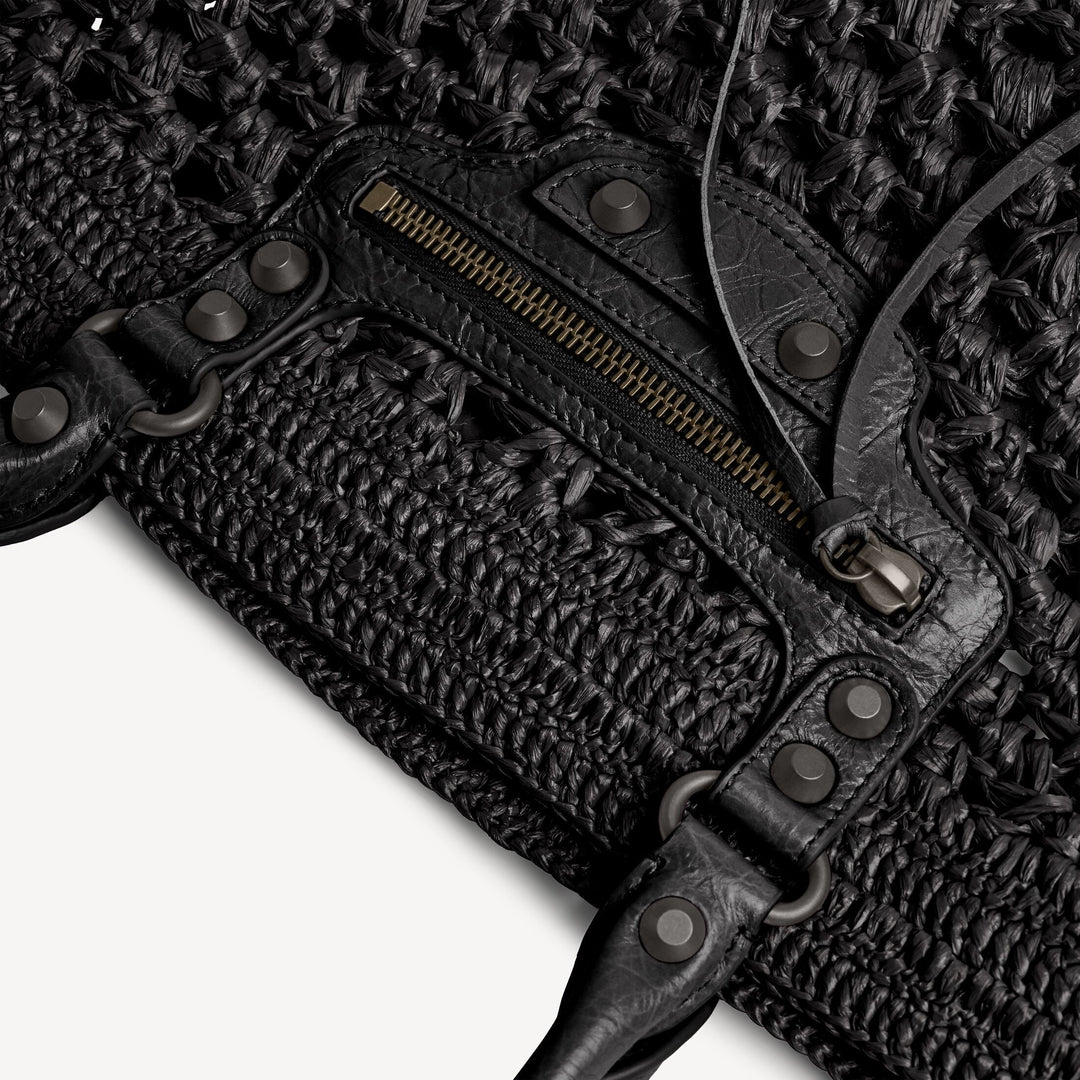 Close-up of a textured black leather bag with a zipper on a textured black background