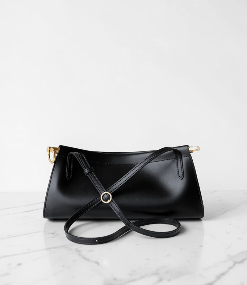 Black handbag with a strap on a light gray background