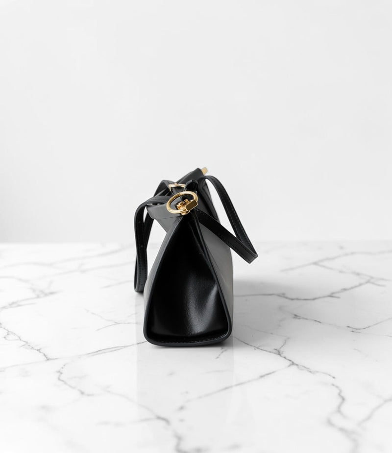 Black handbag with gold accents on a marble surface