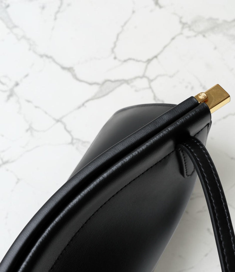 Black handbag with gold clasp on a marble surface