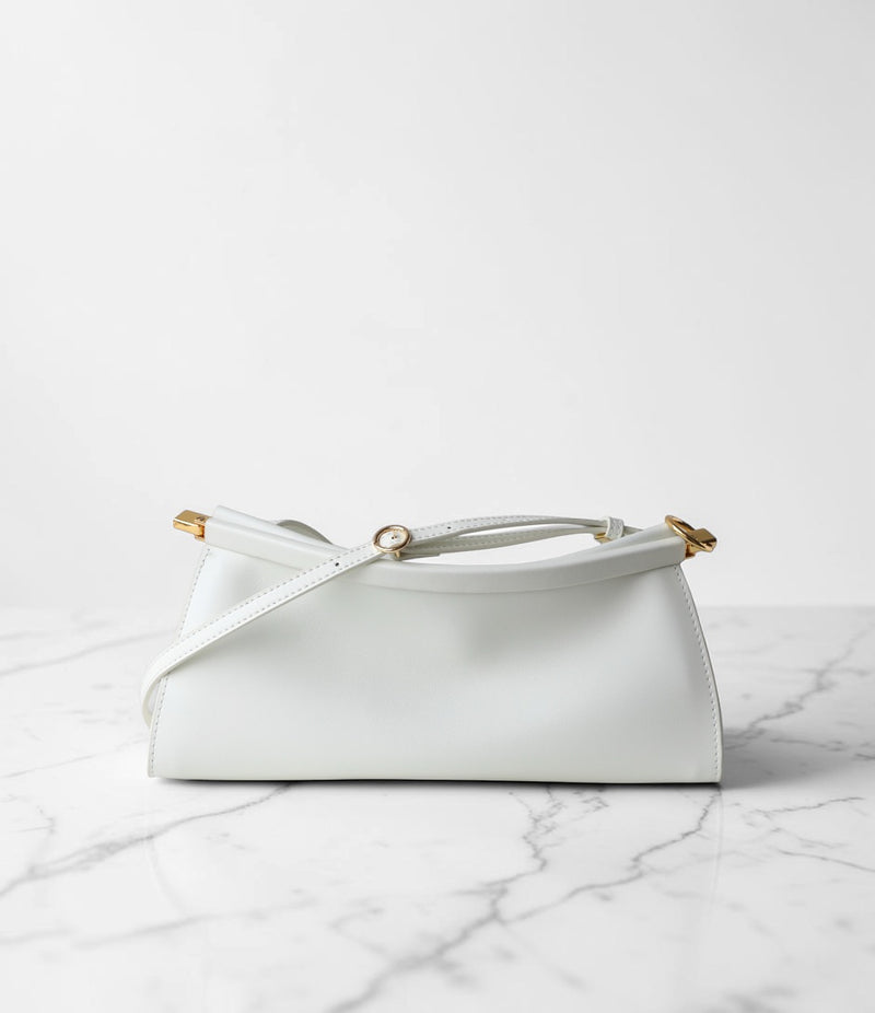 White handbag with gold accents on a marble surface