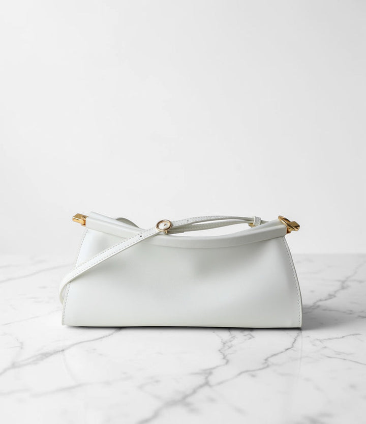 White handbag with gold accents on a marble surface