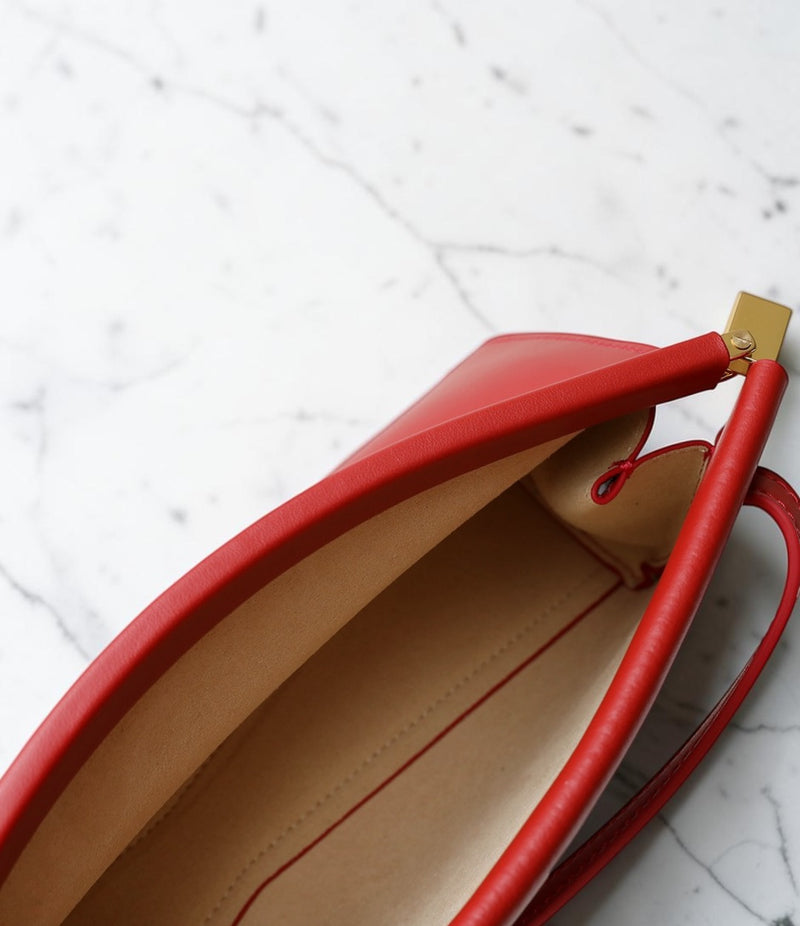 Close-up of a red handbag with a gold clasp on a marble surface