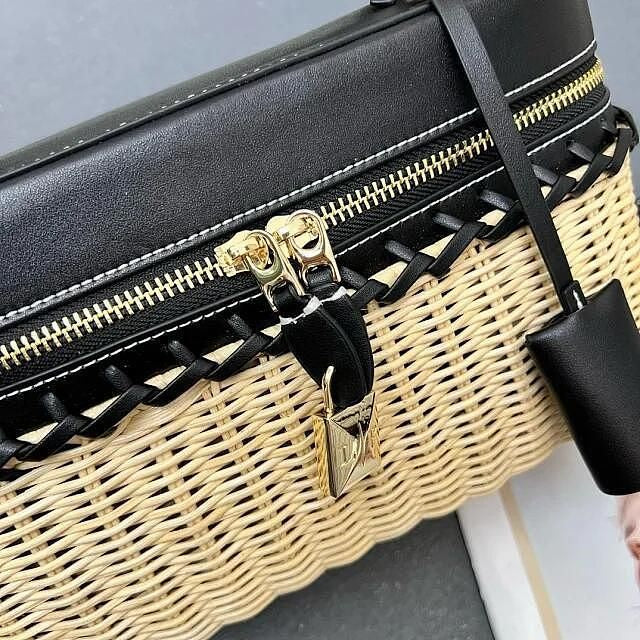 Black and wicker handbag with gold zipper and lock on a gray background