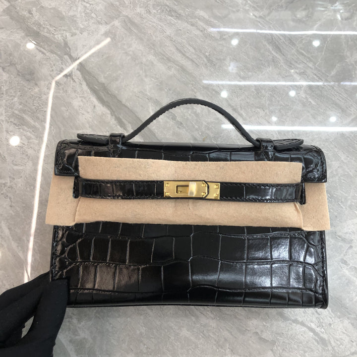 Black crocodile skin handbag with beige interior on a gray tiled floor.