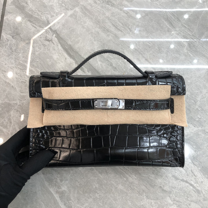 Black crocodile-patterned handbag on a gray marble surface