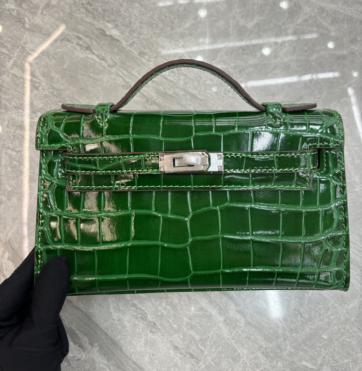 Mini croc-embossed pochette front view showing structured flap and silver clasp closure
