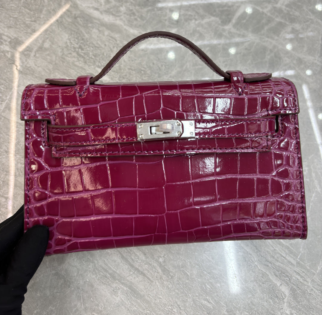Pink croc-embossed mini flap pochette with single top handle product shot white background
