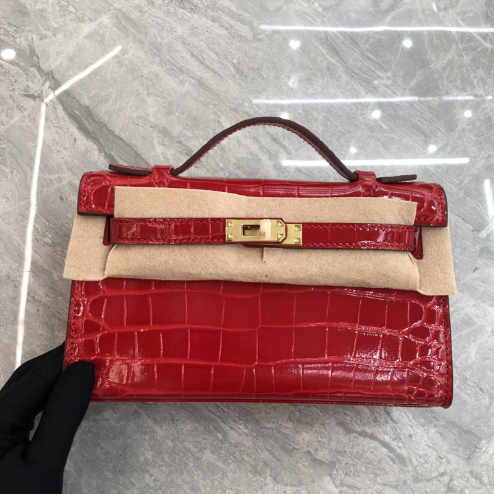 Green glossy crocodile-embossed structured mini bag angle view showing top handle detail
