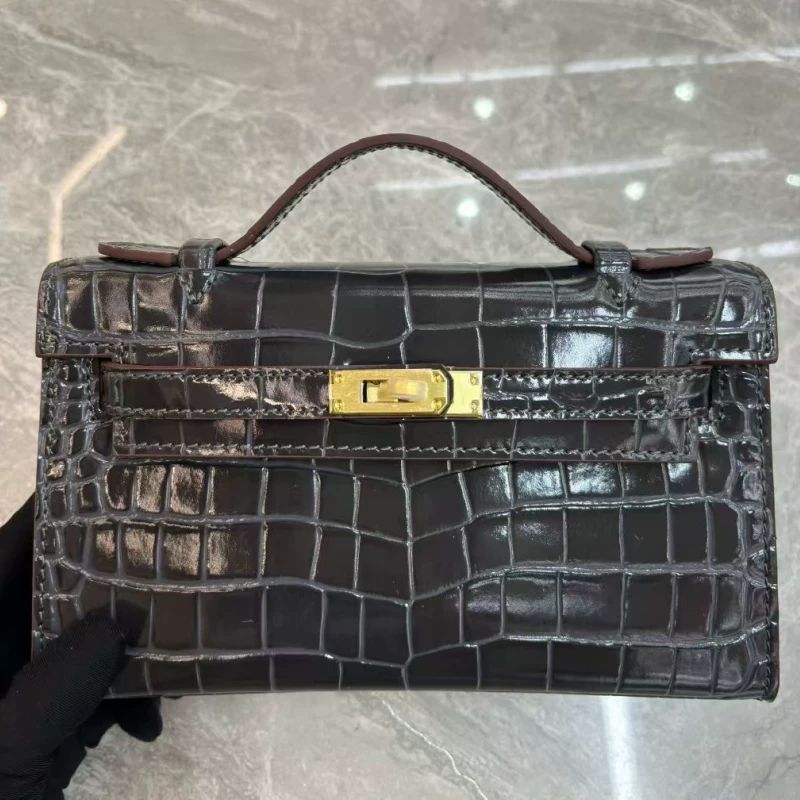 Purple glossy croc-embossed leather pochette flat lay on neutral marble surface
