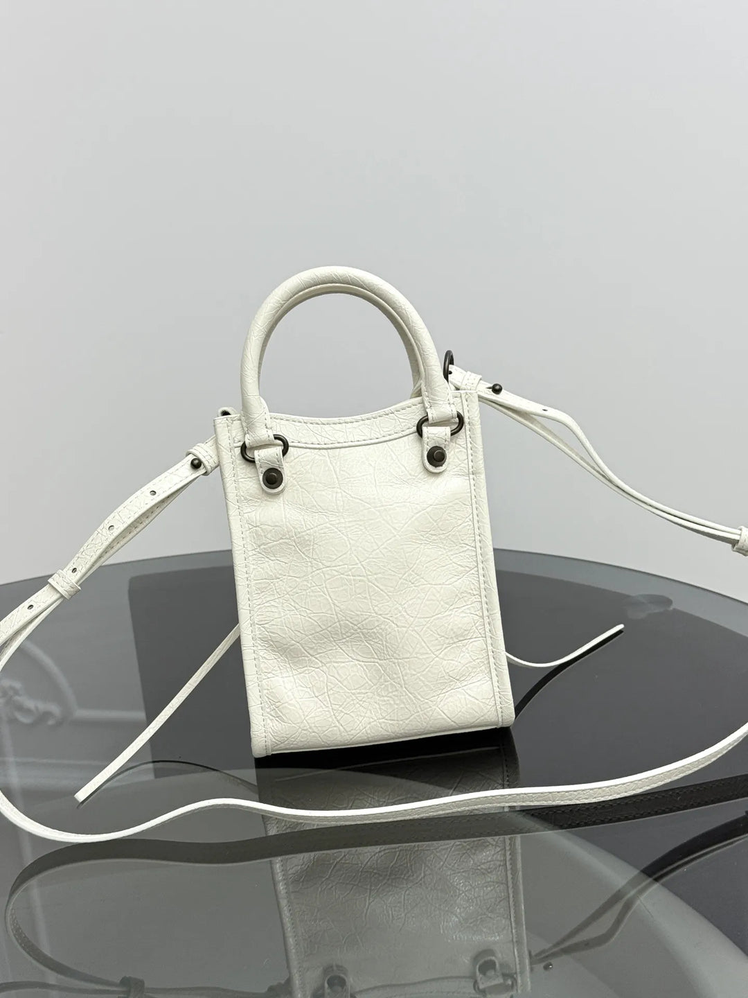 Vertical leather phone crossbody bag side view showing compact depth and hasp closure