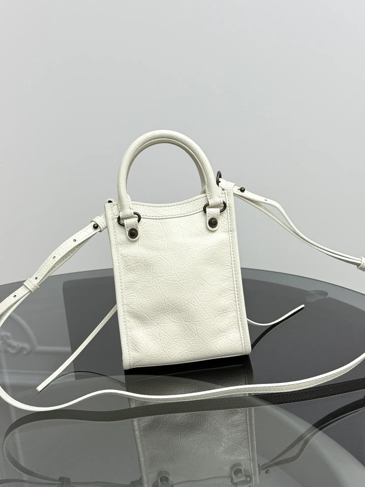 Vertical leather phone crossbody bag side view showing compact depth and hasp closure