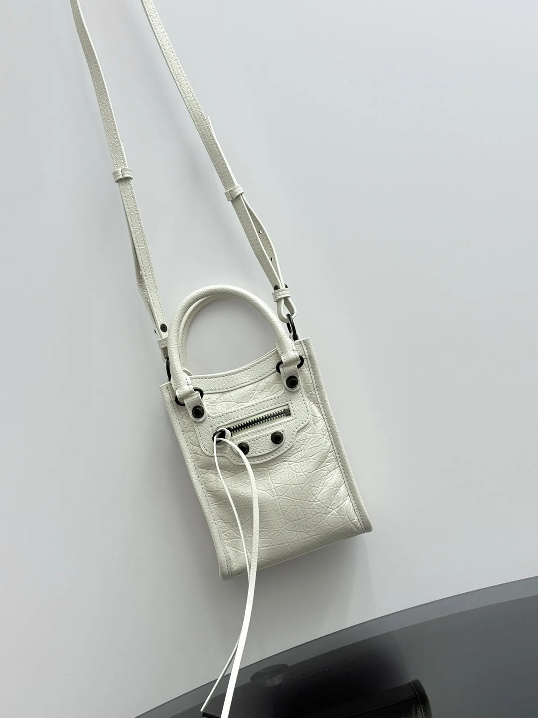 Black crinkled leather mini tote bag lifestyle shot carried crossbody on shoulder