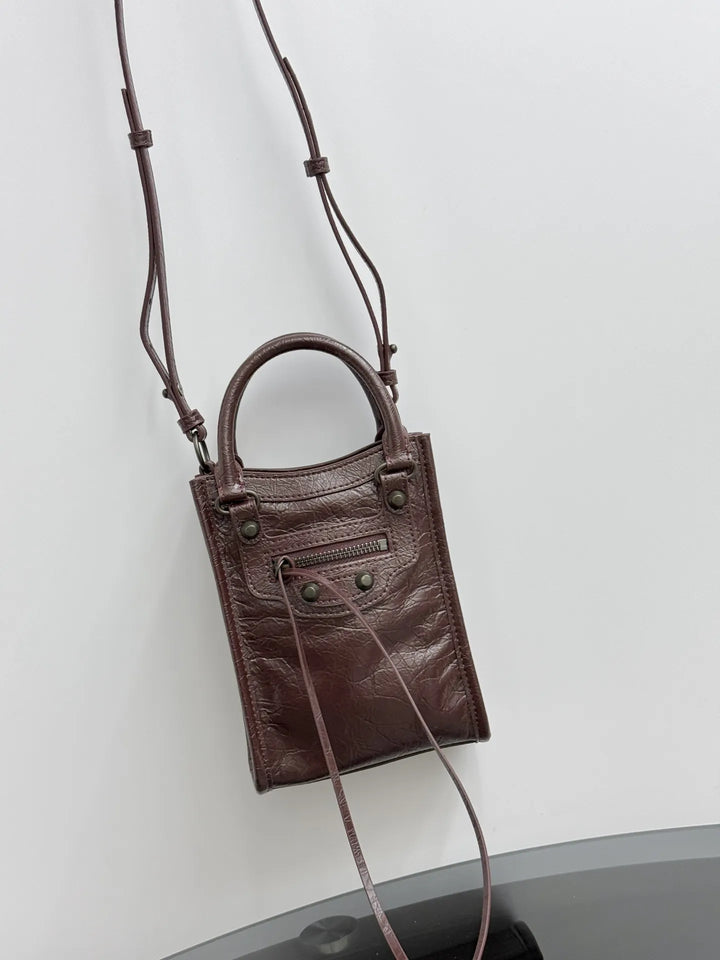 Brown crinkled leather vertical phone bag flat lay showing compact silhouette and strap