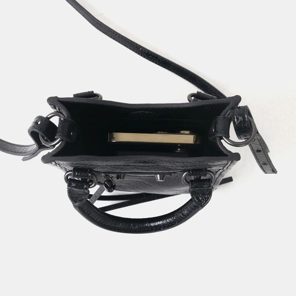 Black textured leather handbag shown from a top-down view, featuring a top handle, shoulder strap, and a gold-toned metal accessory inside the open bag.