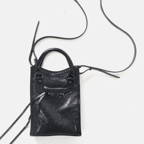 A small black leather top-handle handbag with a zippered front pocket and long thin shoulder straps, photographed on a plain white background.