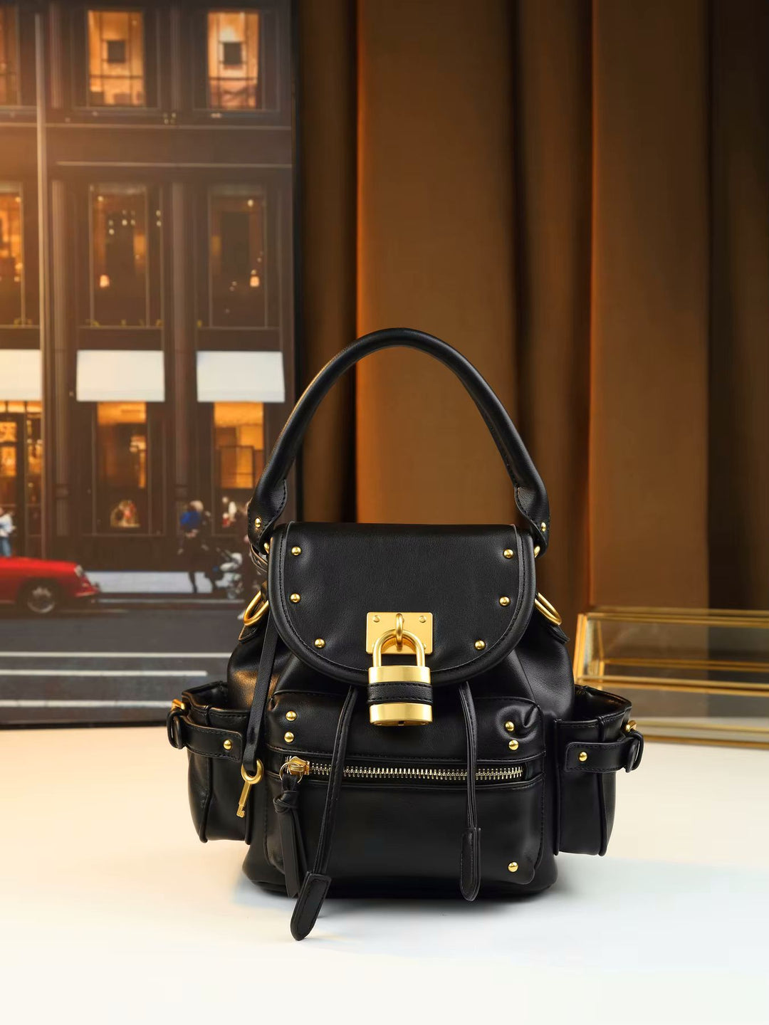 Padlock flap bag angle view highlighting studded flap edge and front zip pocket below lock
