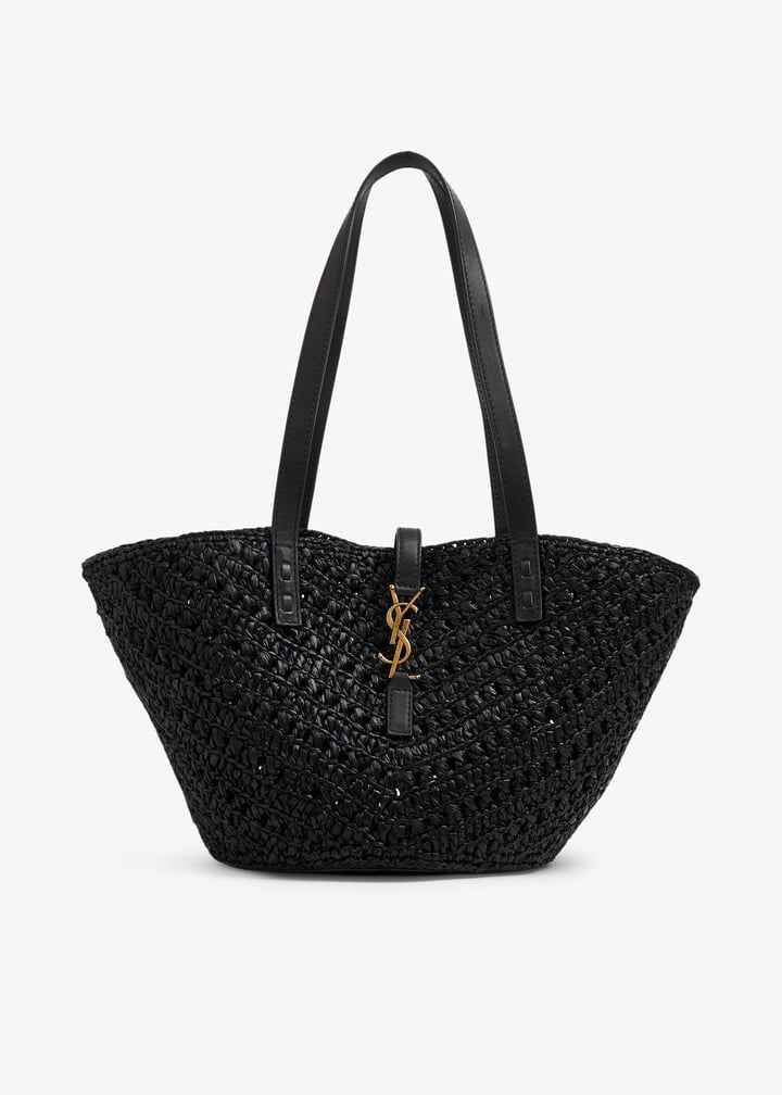 Close-up detail of leather shoulder strap and stud hardware on natural raffia basket bags