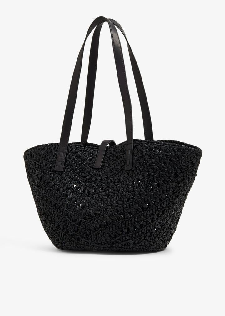 Natural raffia open weave tote bag flat lay on linen surface with sunglasses and sunscreen
