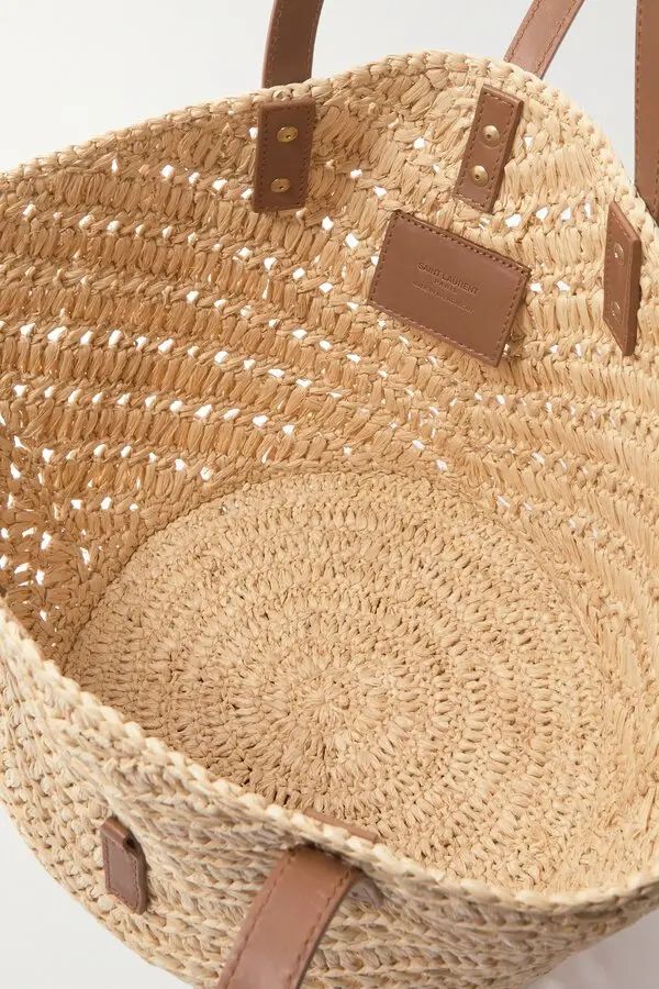 Small raffia basket tote with leather straps lifestyle shot at beachside terrace

