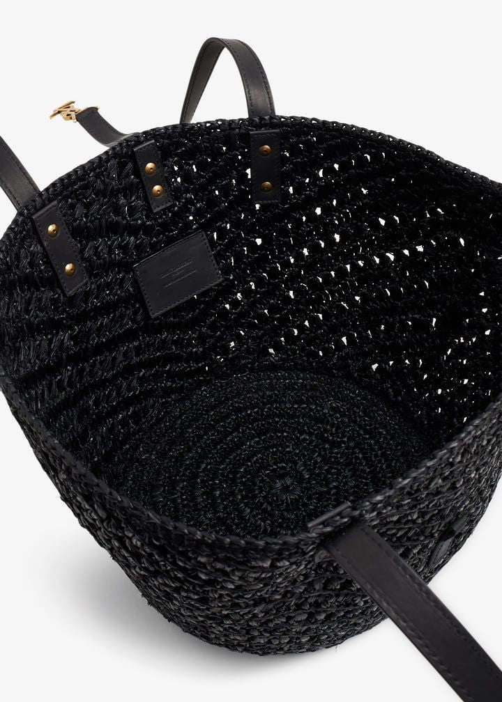 Black woven bag with a strap on a white background