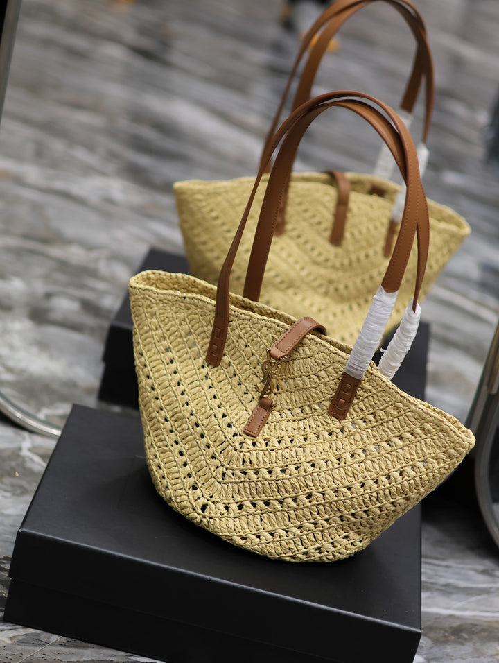 Woven handbag with brown handles on a black stand against a blurred wooden background