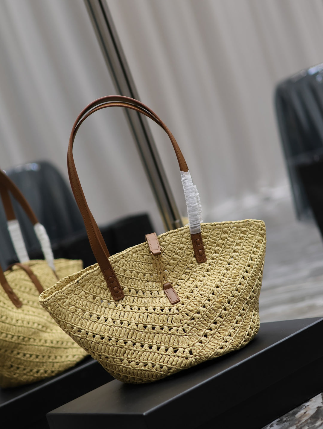 Yellow woven handbag with brown handles on a reflective surface