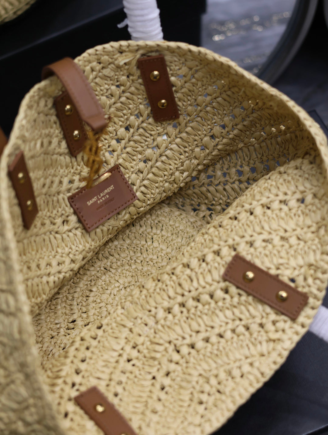 Close-up of a beige crochet bag with brown leather straps and patches.