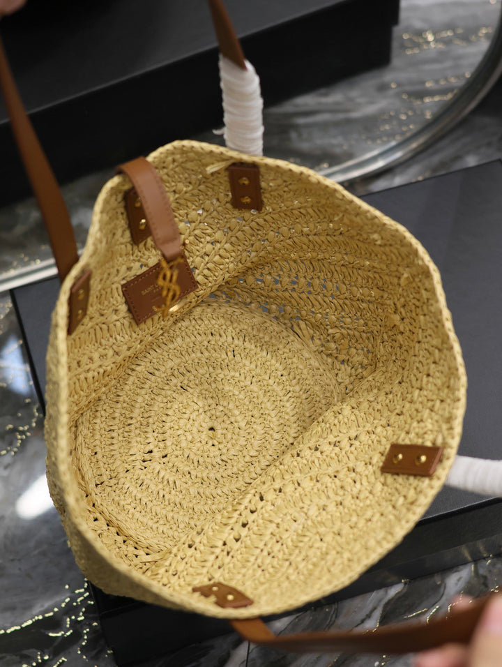 Woven straw bag with leather straps on a reflective surface