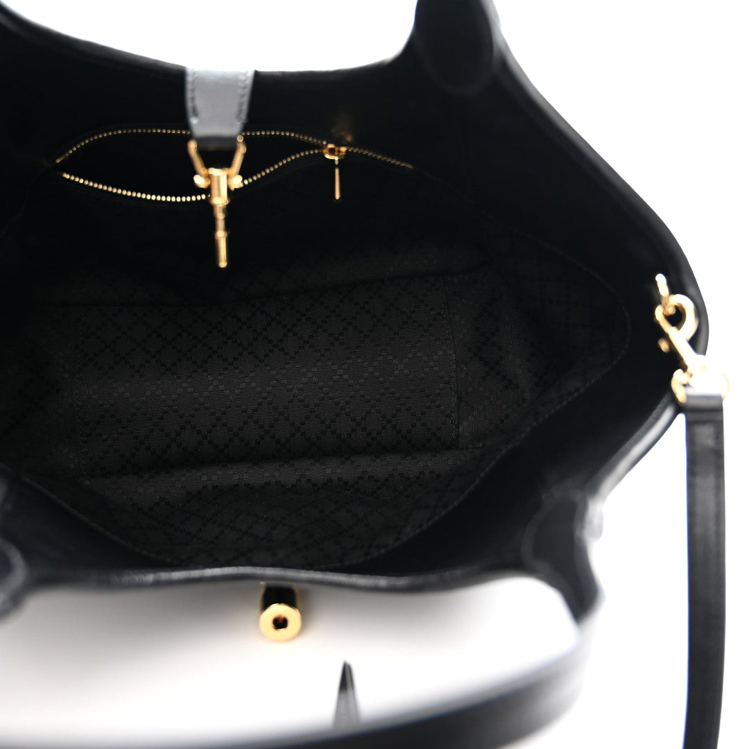 Close-up of a black handbag with gold hardware on a white background