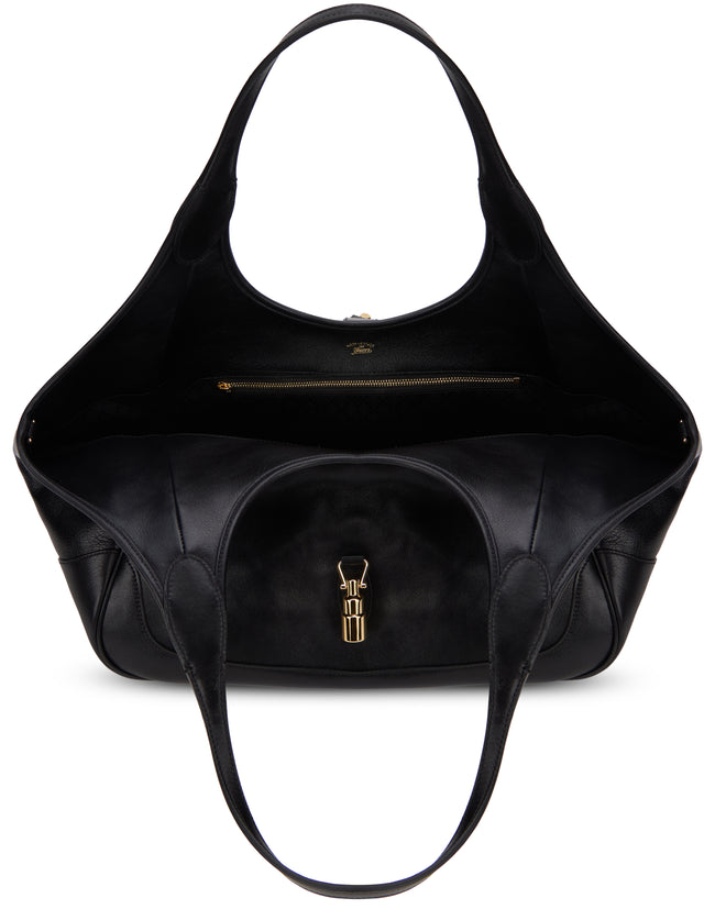 A black leather shoulder bag with a curved top handle, a front zippered pocket with a gold-tone metal clasp, and a gold zippered interior pocket, shown against a plain white background.