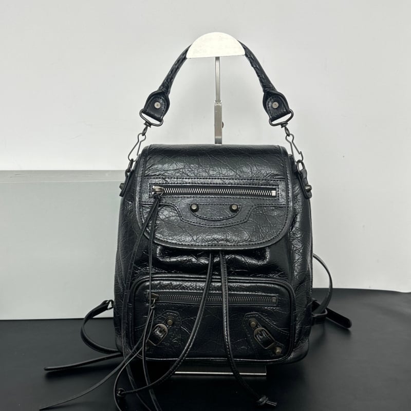 Studded backpack angle view highlighting flap closure drawstring pull and front zip pocket