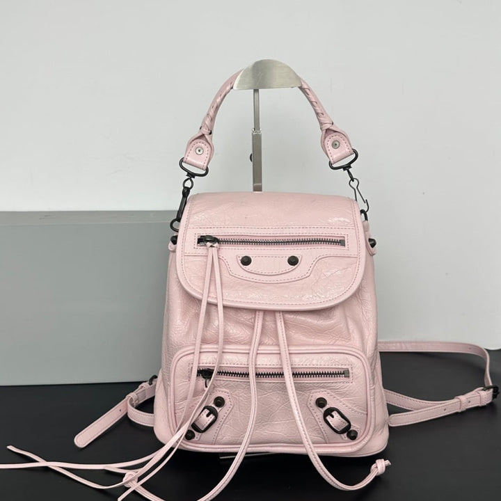 Leather flap backpack side view showing top handle crossbody strap and structured body