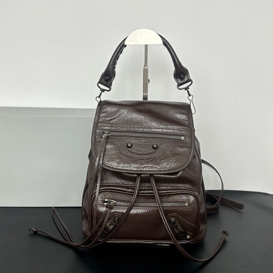 Black studded leather flap backpack product shot on dark reflective surface