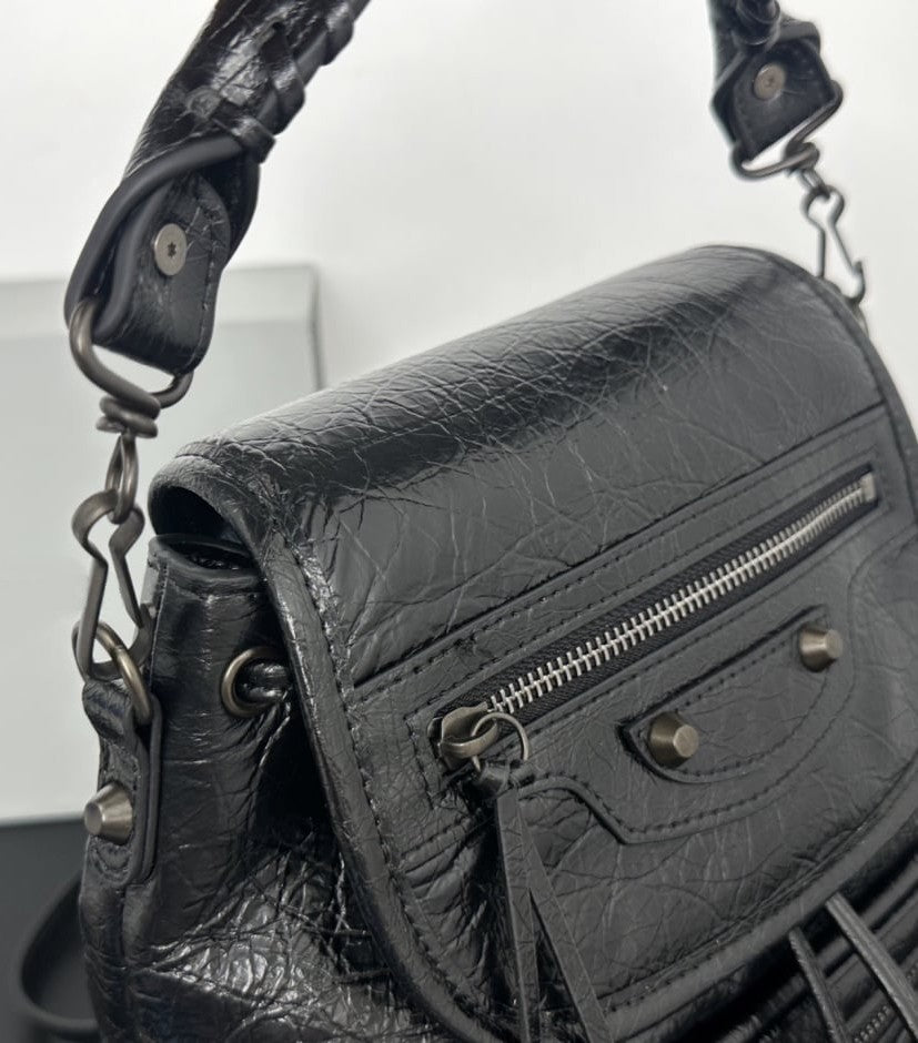 White leather flap backpack close-up of black stud hardware and zip pull tassel detail