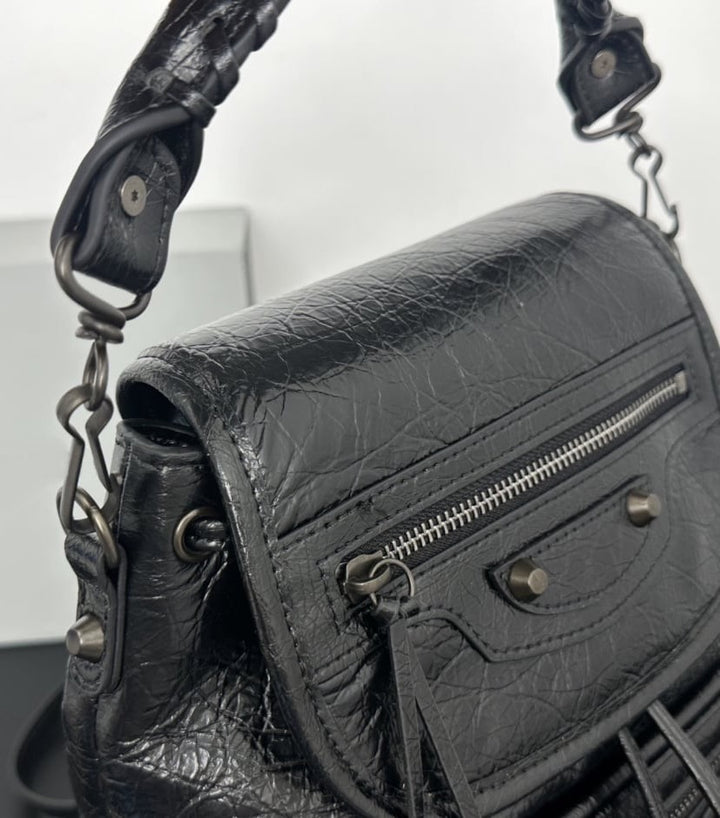 White leather flap backpack close-up of black stud hardware and zip pull tassel detail