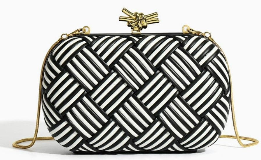 White and gold woven clutch bag angle view highlighting structured oval shape
