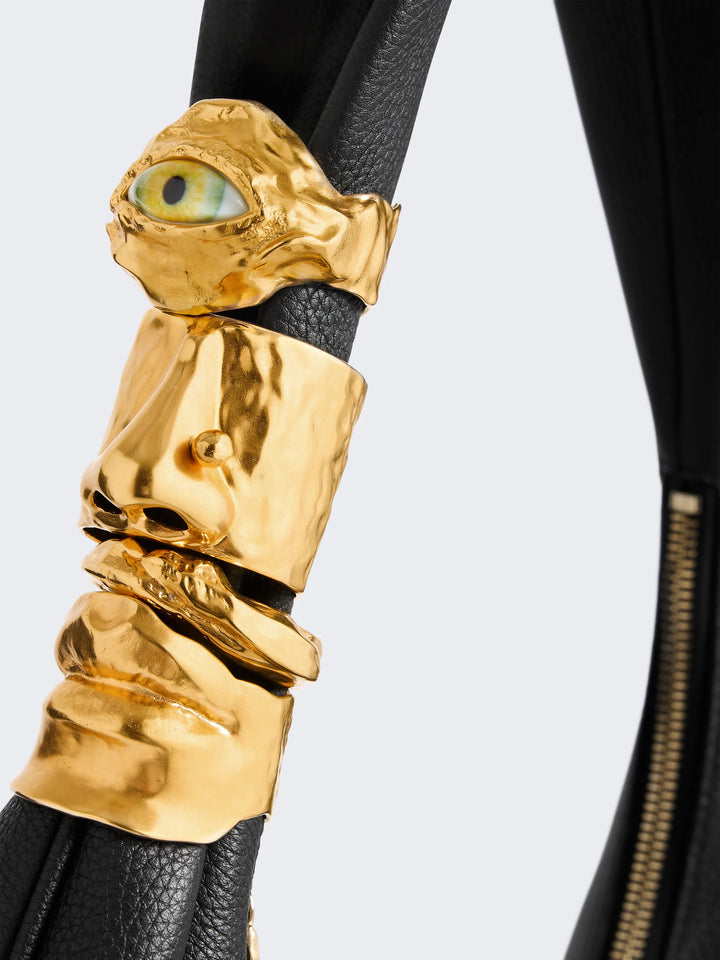 Gold arm cuff with face design on a black background